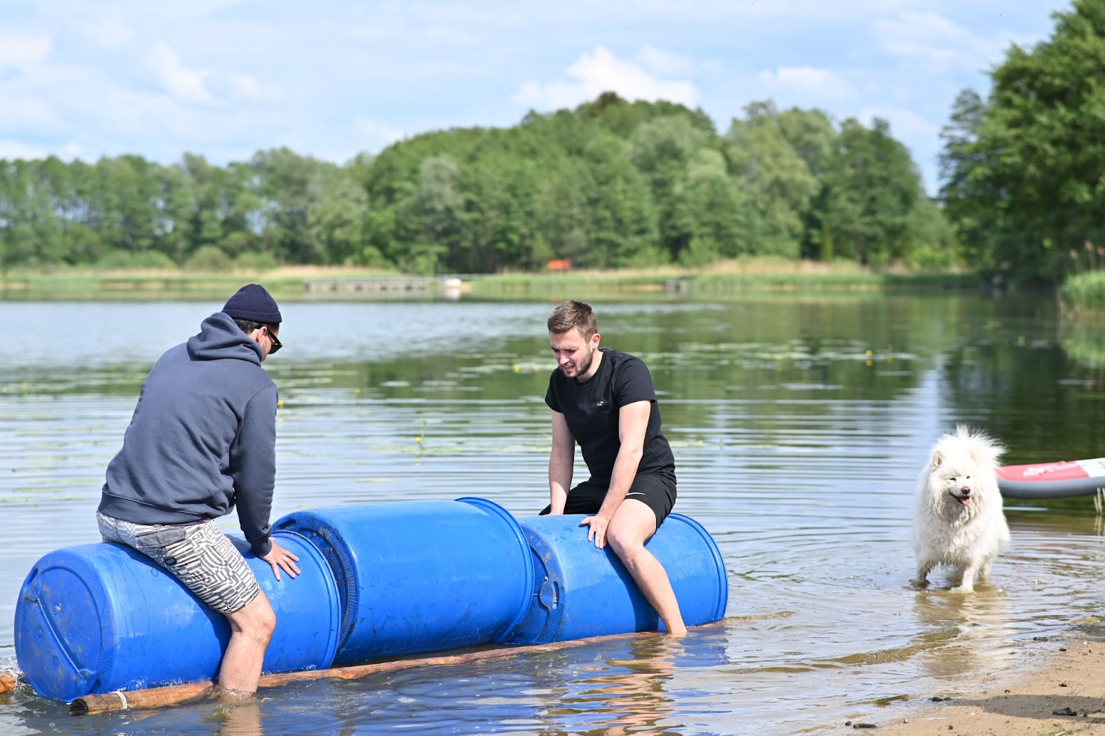 Photo of two Leapsome employees testing the raft they built by sitting on barrels in a lake.