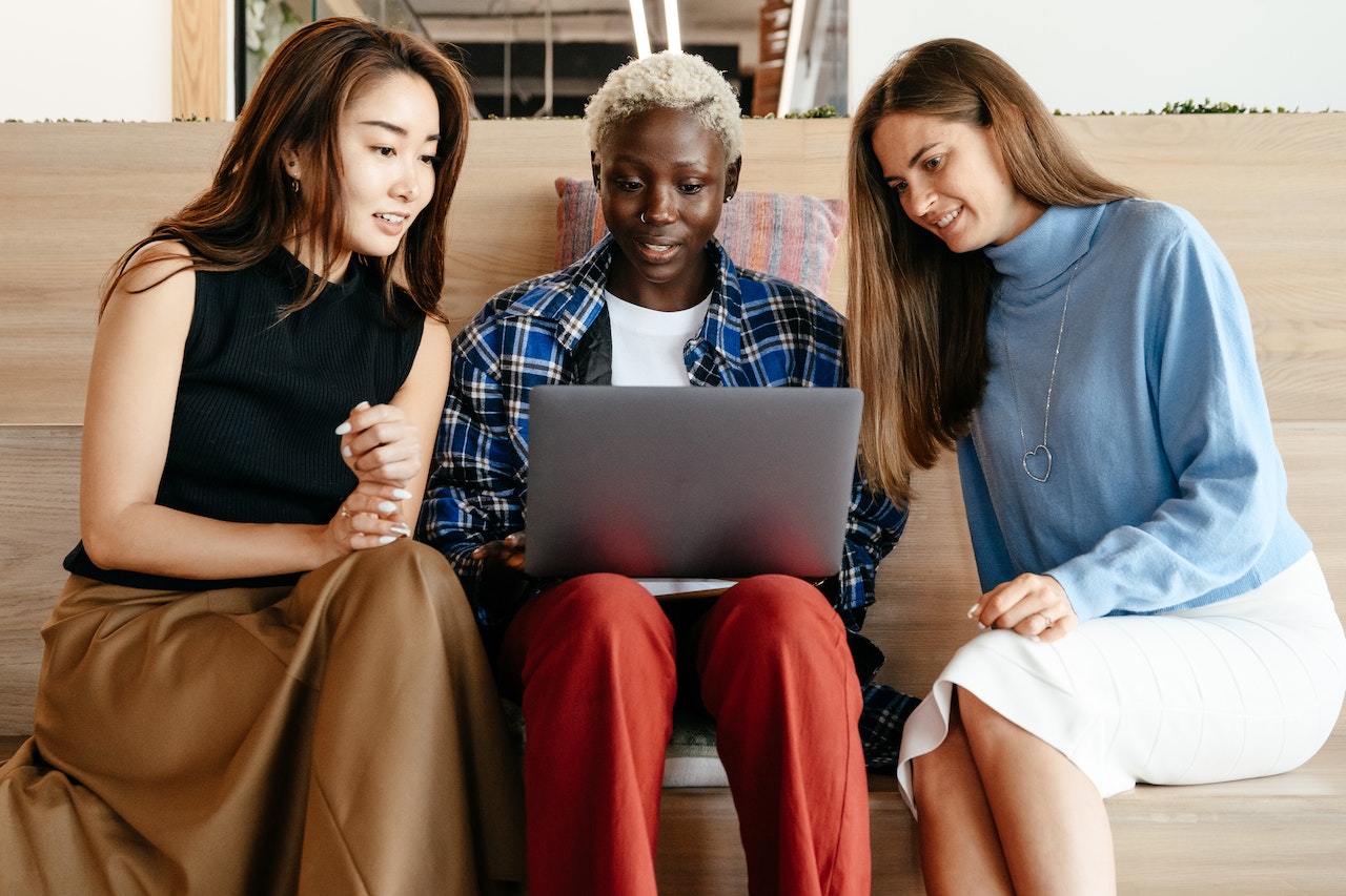 Photo of three remote employees sitting together and looking at a laptop 