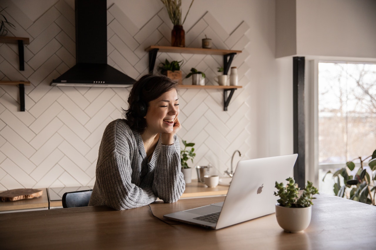 Photo of smiling woman having a video conference call from her kitchen