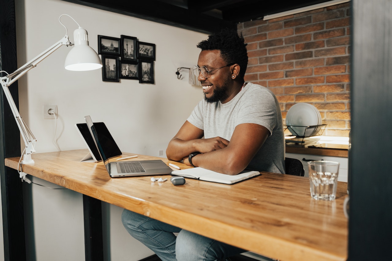 Photo of a remote employee working from home with his laptop, smiling during a video conference