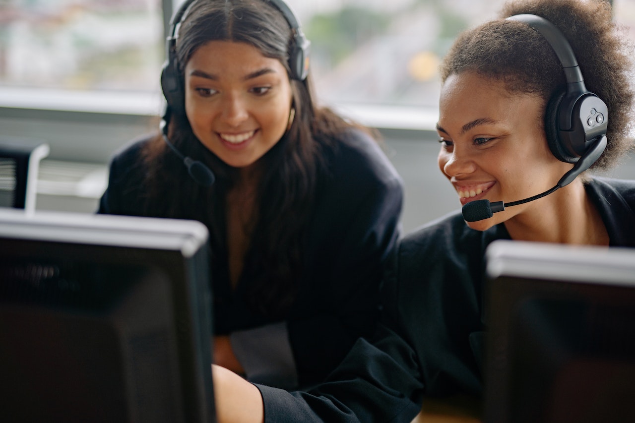 Photo of two customer care employees sitting at their computers between calls.