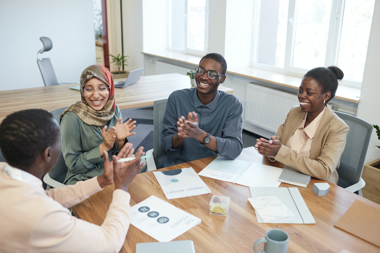 Photo of professionals applauding a promotion announcement during a meeting.