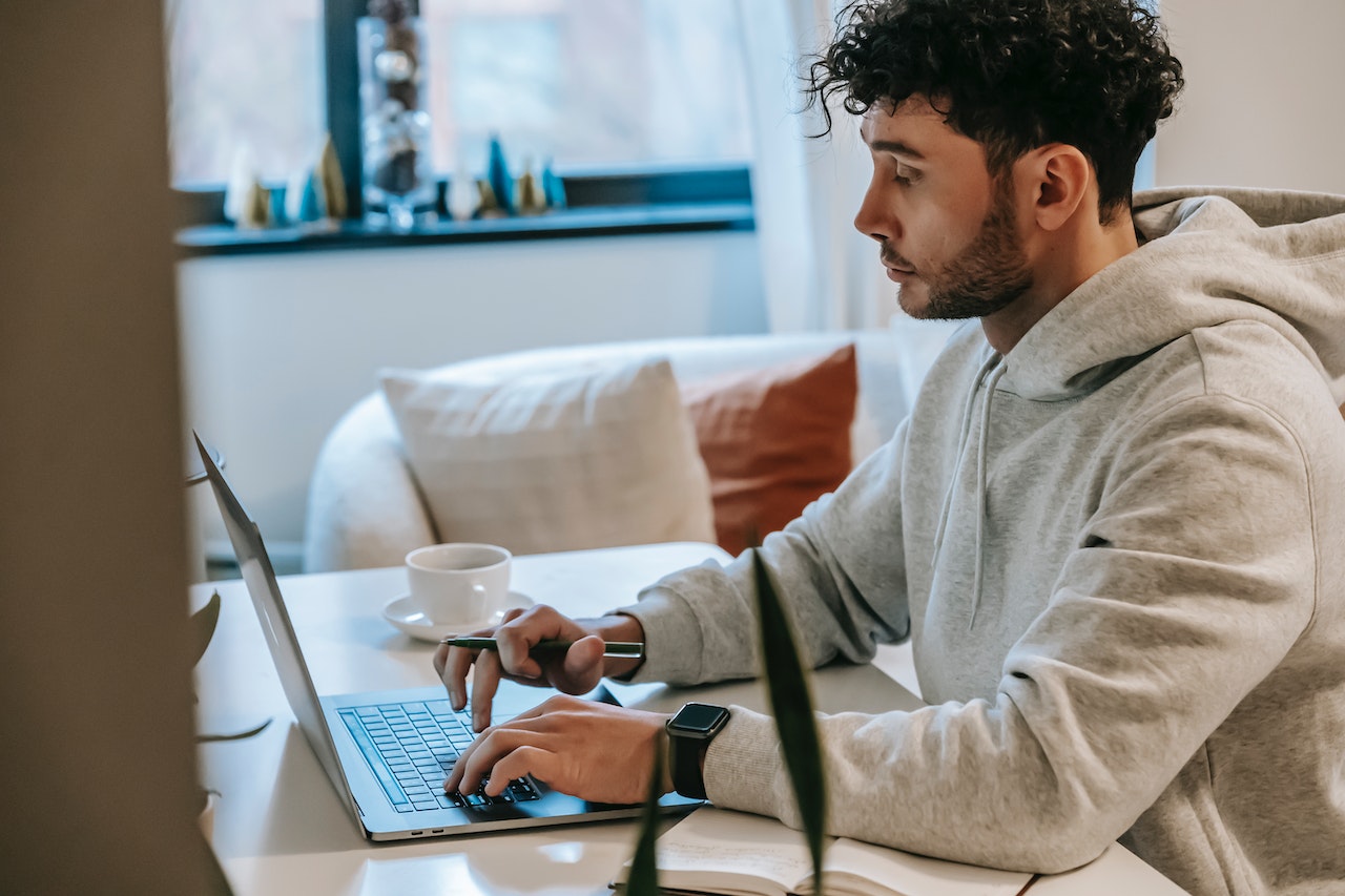 A photograph of a person sitting behind a desk, working on their laptop.