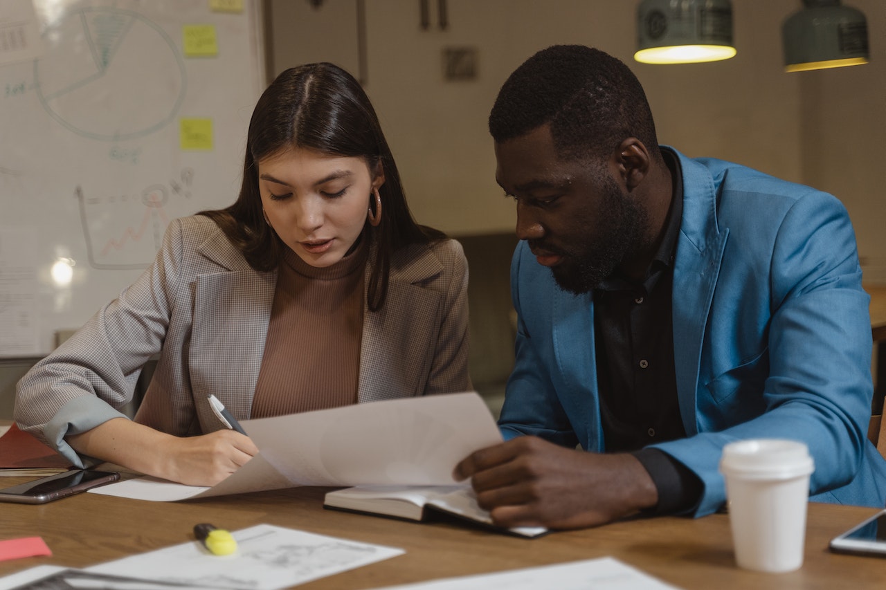 A photo of two employees looking at a document together.