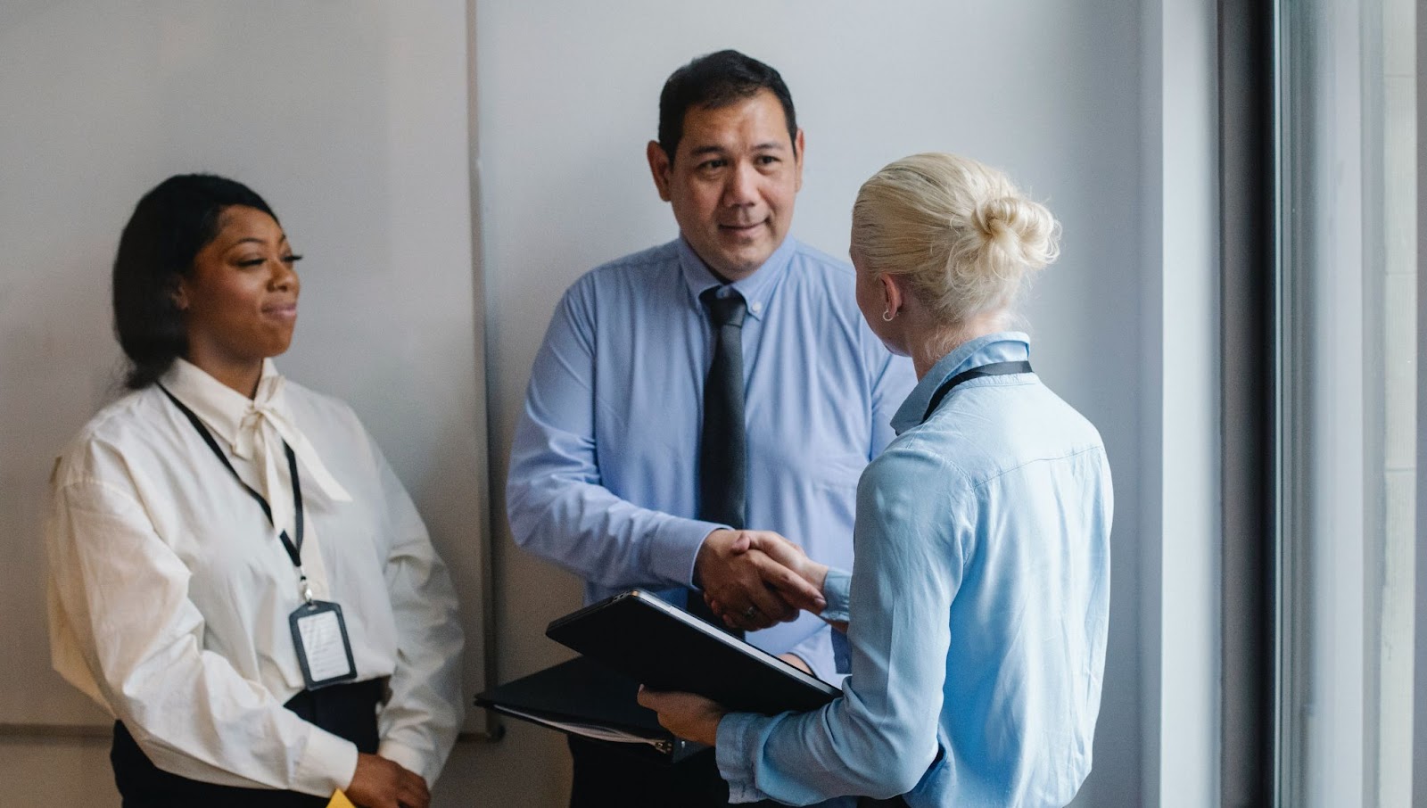 A screenshot of three employees standing together, two of them shaking hands.