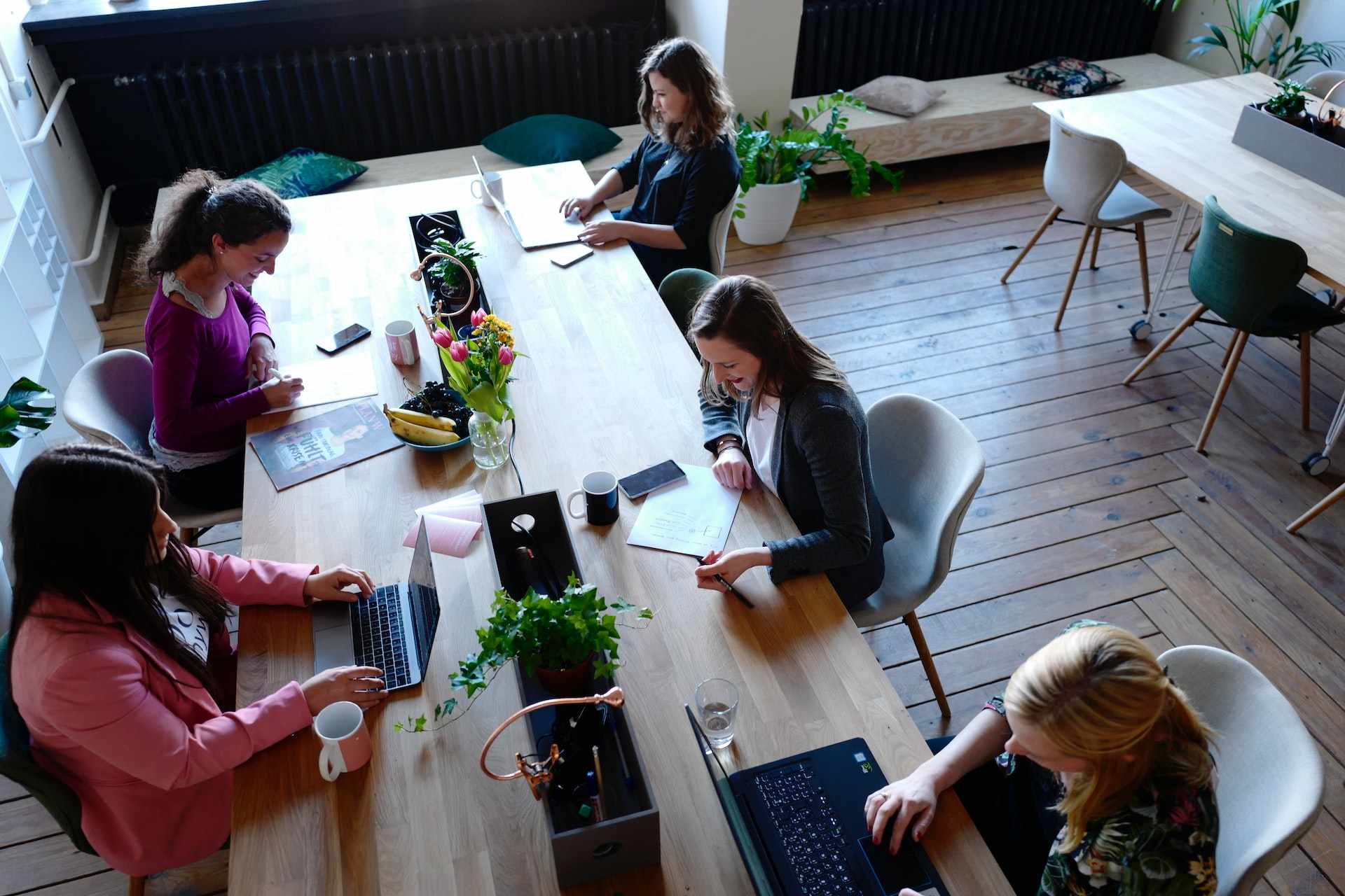 Photo of five woman at a coworking space, all doing their work at laptops at a shared coworking table