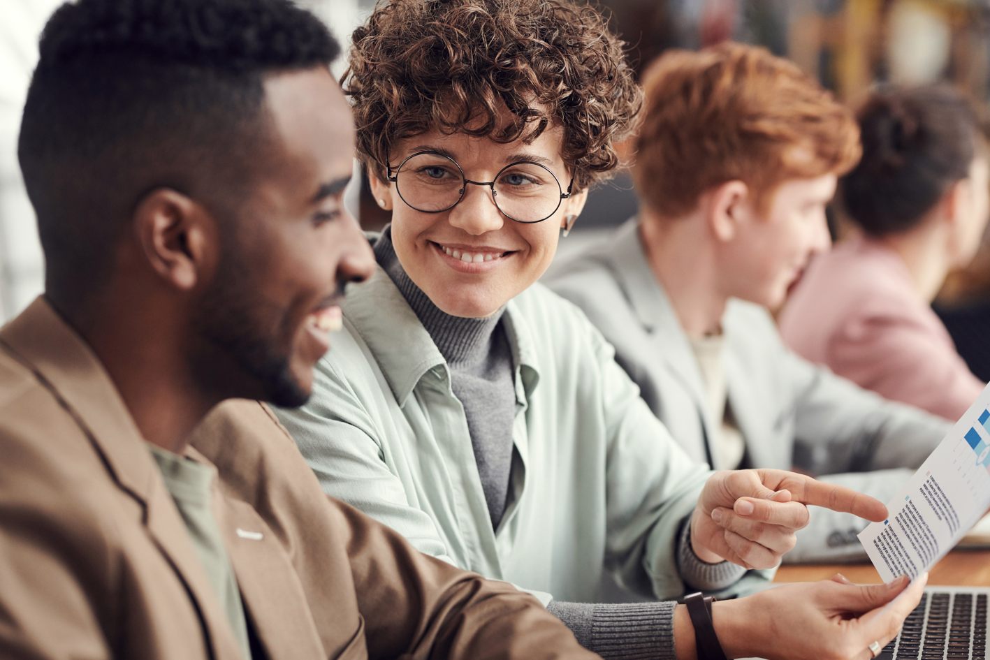 Photo of one employee smiling at another while working together