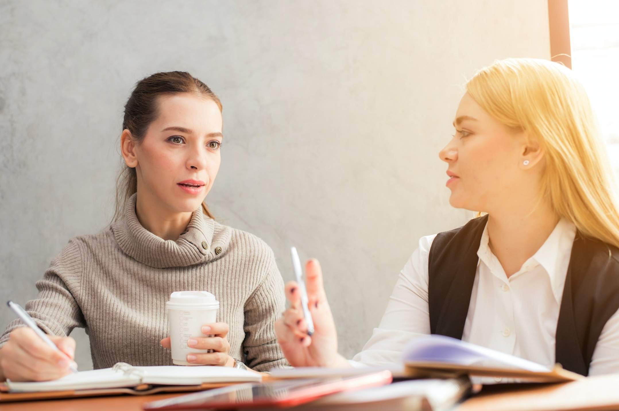 A photo of two professionals having a conversation and writing notes.