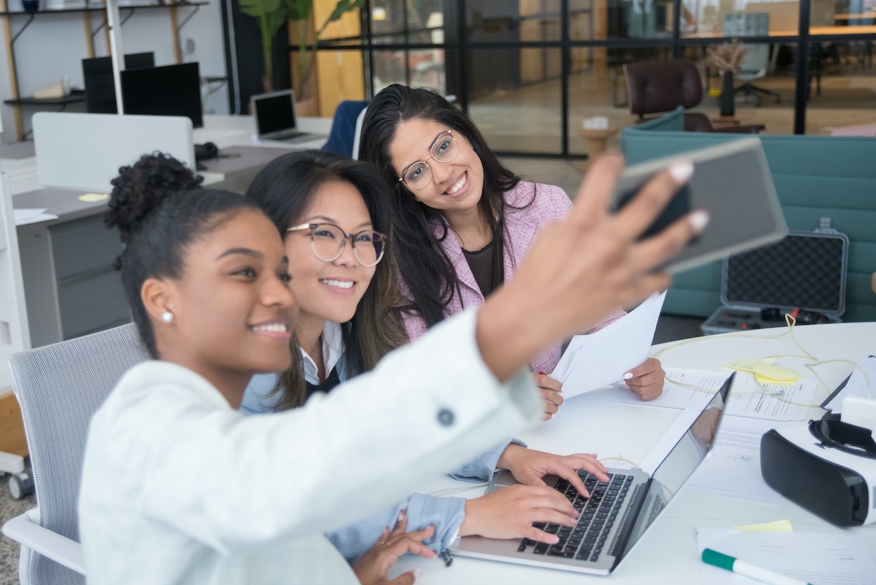 Photo of a group of work friends taking a selfie at their desk.