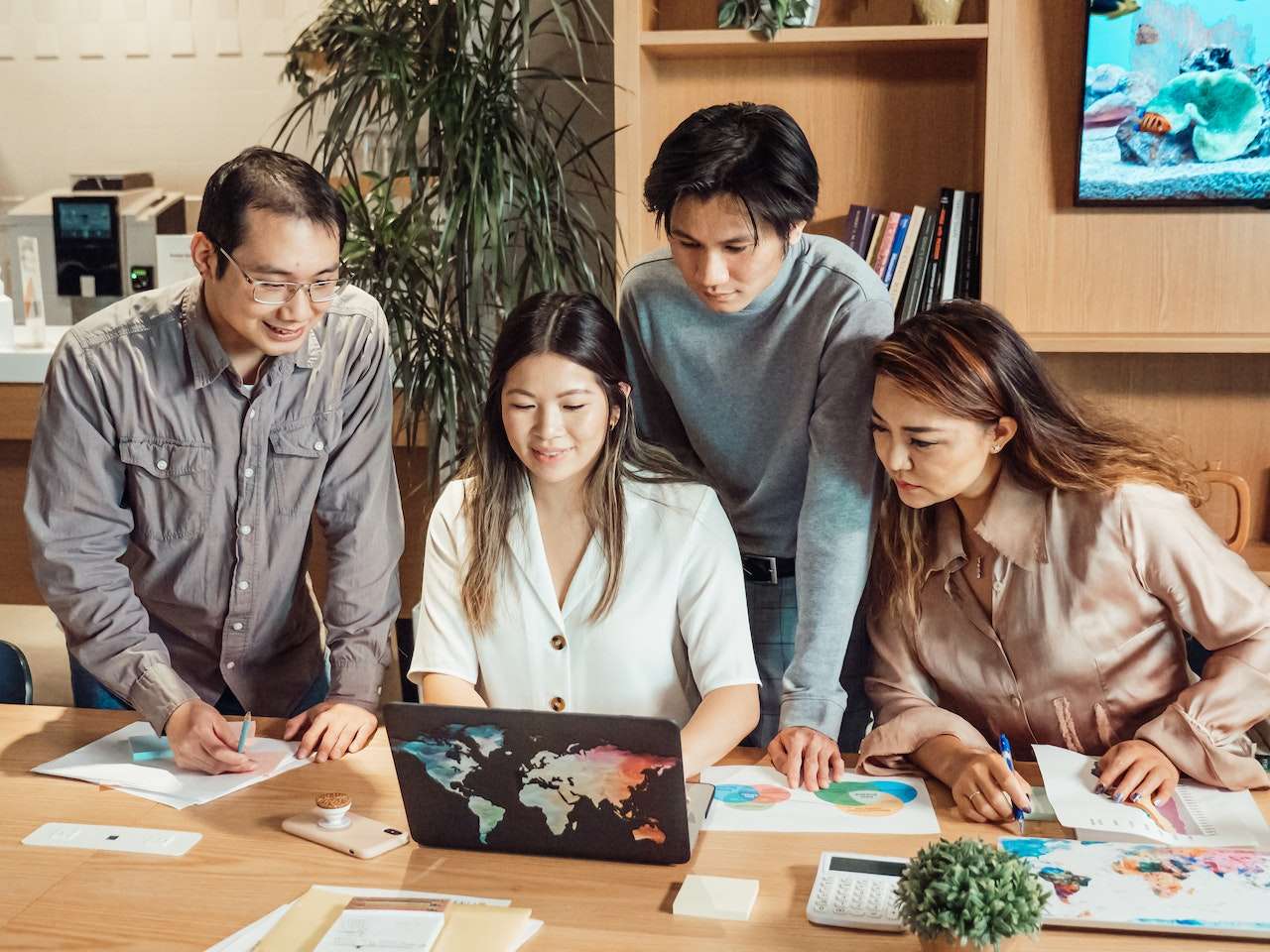 A photo of four employees looking at a laptop.