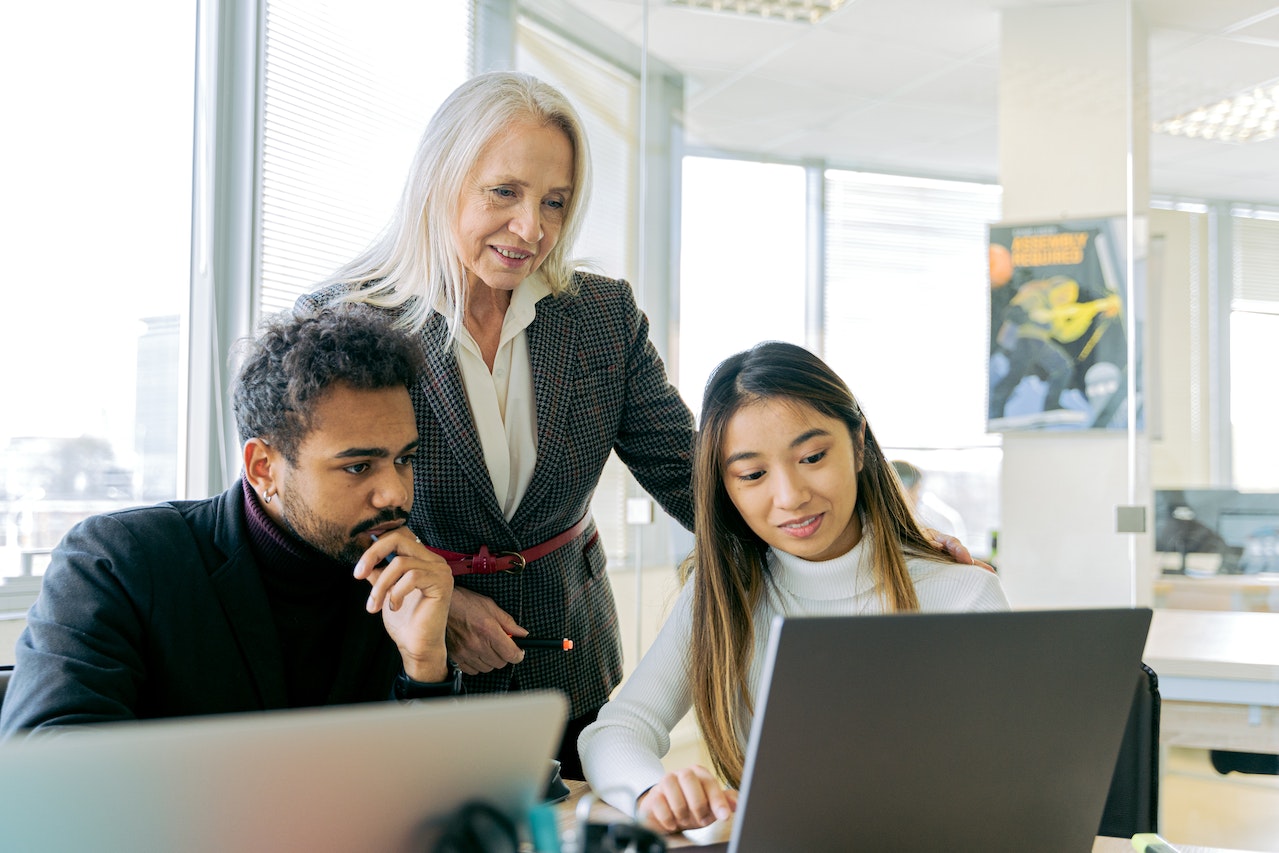 A photo of three employees working together on a project.