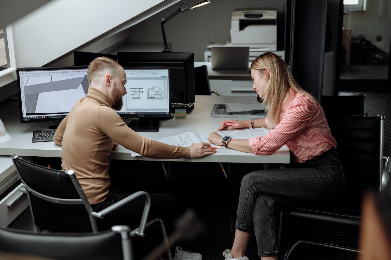 A photo of two professionals working together at a desk.