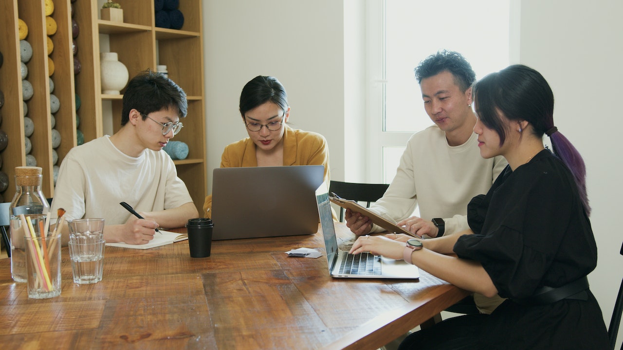 A photo of a group of professionals working together at a wooden table.