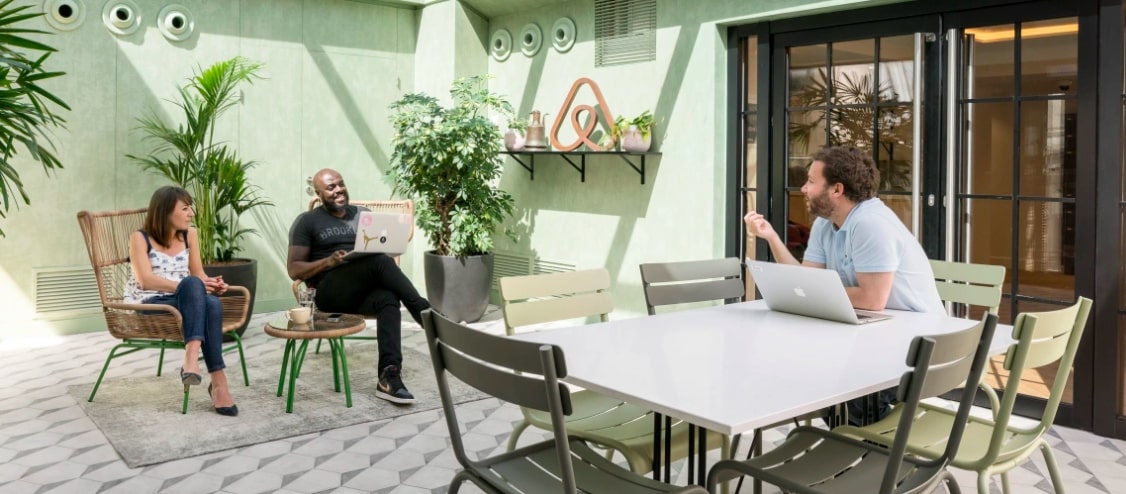 A photo of three Airbnb employees working in an outside office space.