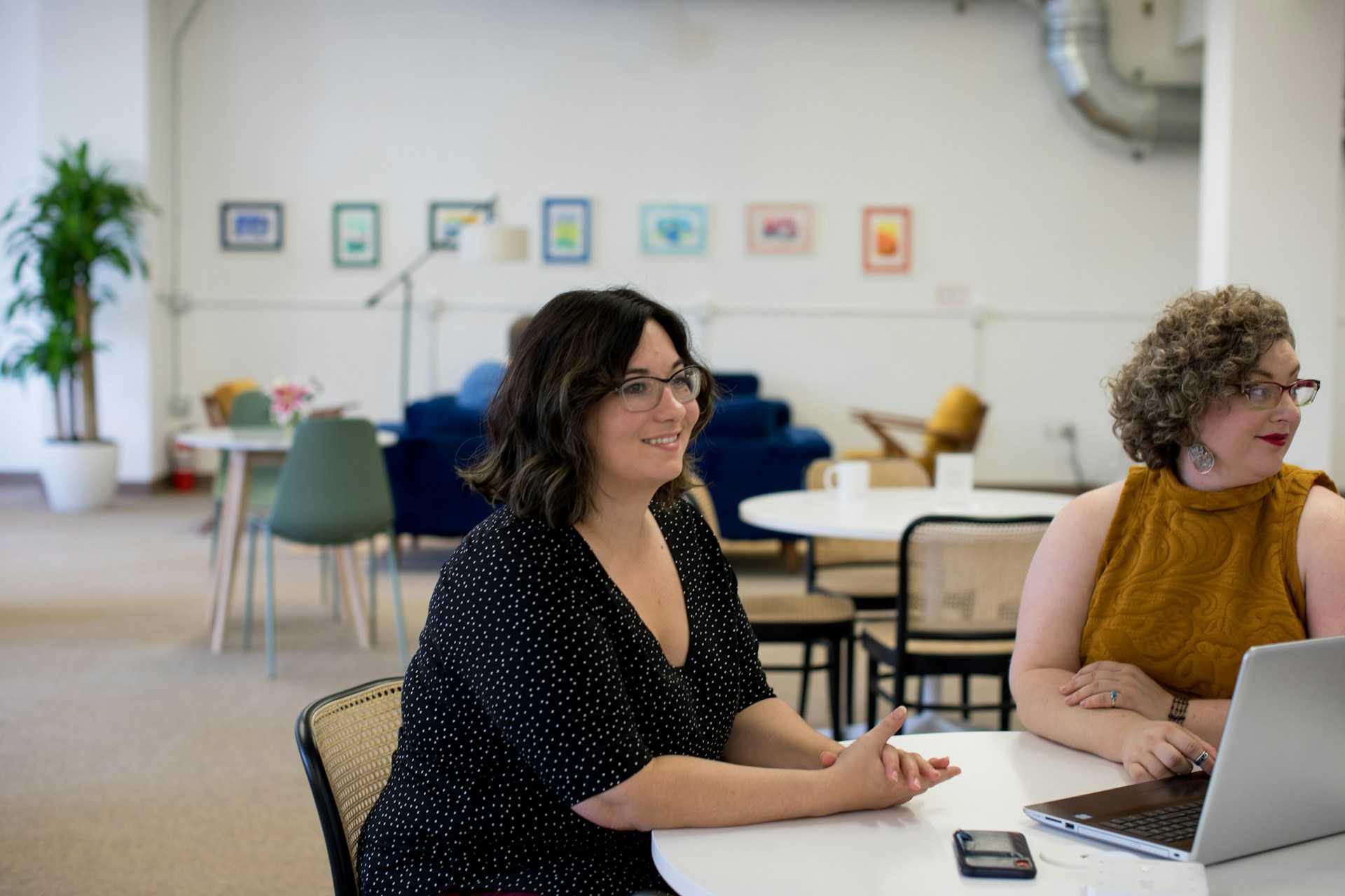 An image of two employees sitting in a meeting, smiling.