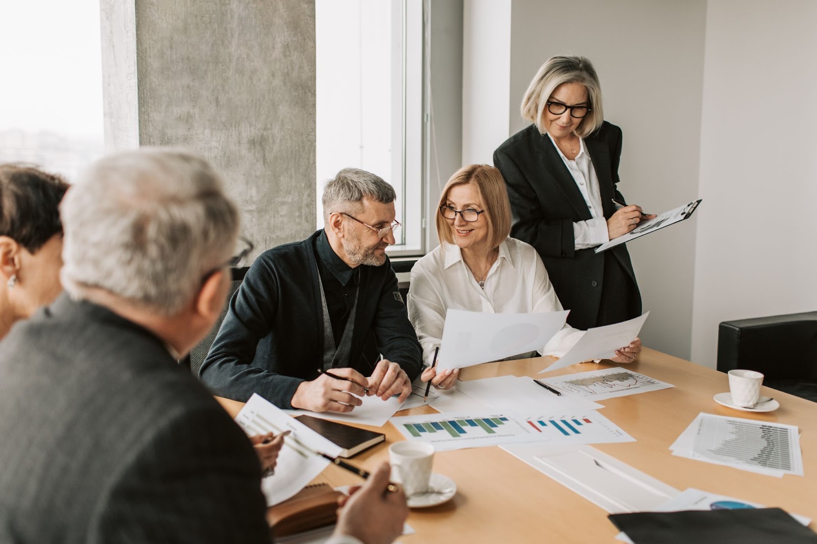 Photo of employees in a meeting, sitting around a table with documents on it.