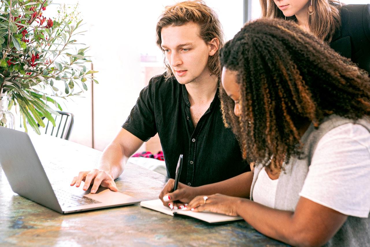 Photo of three employees conducting research together at a laptop.