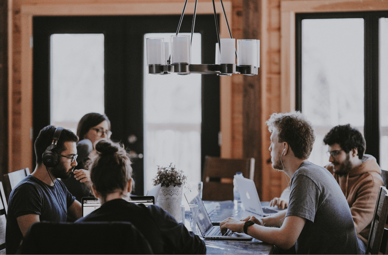 Photo of a group of employees sitting around a big table, working on their laptops.